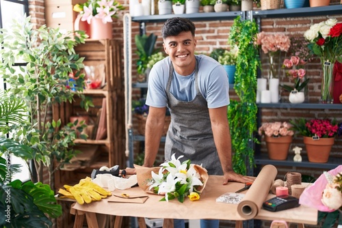 Young hispanic man florist smiling confident standing at flower shop