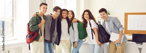 Fotografie Portrait of a happy cheerful smiling high school students group standing in classroom together and hugging