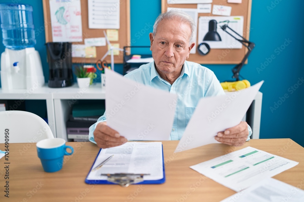 Middle age grey-haired man business worker reading document at office Middle age grey-haired man business worker reading document at office