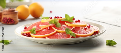 Colorful citrus fruit salad with grapefruit slices, pomegranate seeds, on a white plate with yellow linen. Space for copying.