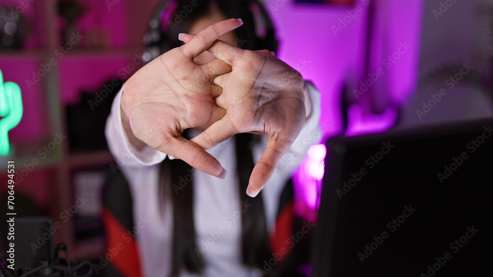 Young asian woman making hand gesture in a neon-lit gaming room at night