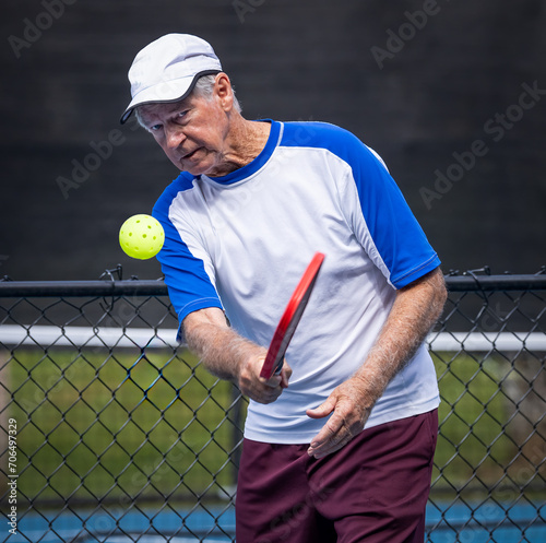 Male senior pickleball player with eye on the ball
