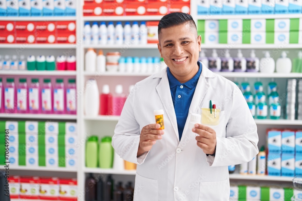 Young latin man pharmacist smiling confident holding pills bottles at pharmacy Young latin man pharmacist smiling confident holding pills bottles at pharmacy