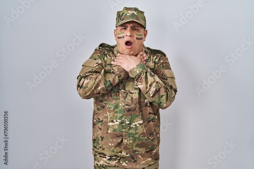 Hispanic young man wearing camouflage army uniform shouting and suffocate because painful strangle. health problem. asphyxiate and suicide concept.