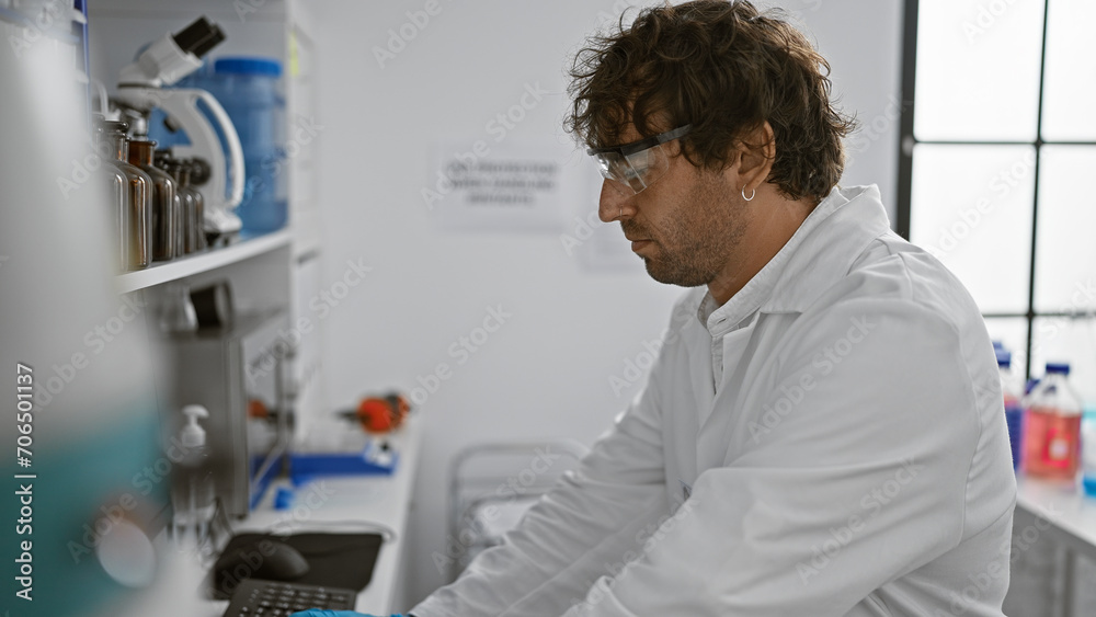 A focused man in safety glasses works meticulously in a modern laboratory with scientific equipment.