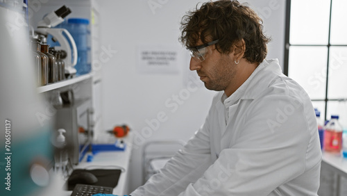 A focused man in safety glasses works meticulously in a modern laboratory with scientific equipment.