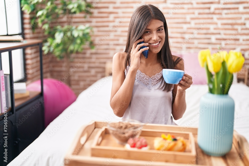 Young beautiful hispanic woman having gift breakfast talking on smartphone at bedroom Young beautiful hispanic woman having gift breakfast talking on smartphone at bedroom