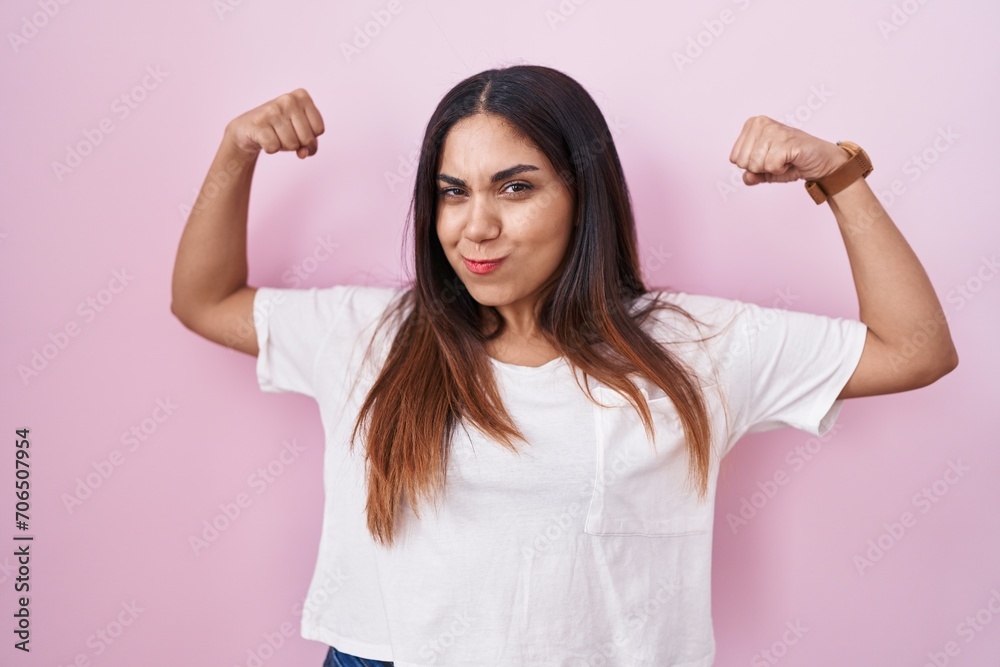 Young arab woman standing over pink background showing arms muscles smiling proud. fitness concept. Young arab woman standing over pink background showing arms muscles smiling proud. fitness concept.