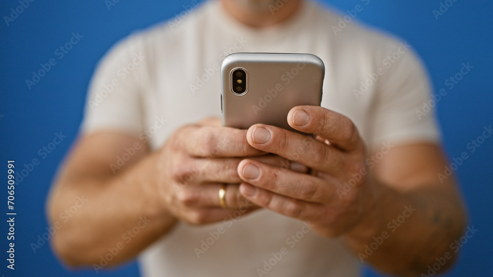 Handsome young man with beard using smartphone against blue backdrop, portraying connectivity and modern lifestyle. Handsome young man with beard using smartphone against blue backdrop, portraying connectivity and modern lifestyle.
