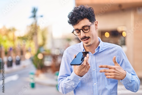 Young caucasian man talking on the smartphone with serious expression at street
