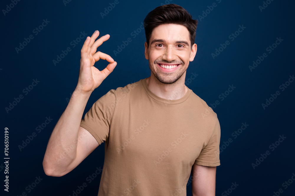 Naklejka premium Photo of cheerful handsome pleasant man with bristle dressed beige t-shirt showing okey nice work isolated on dark blue color background