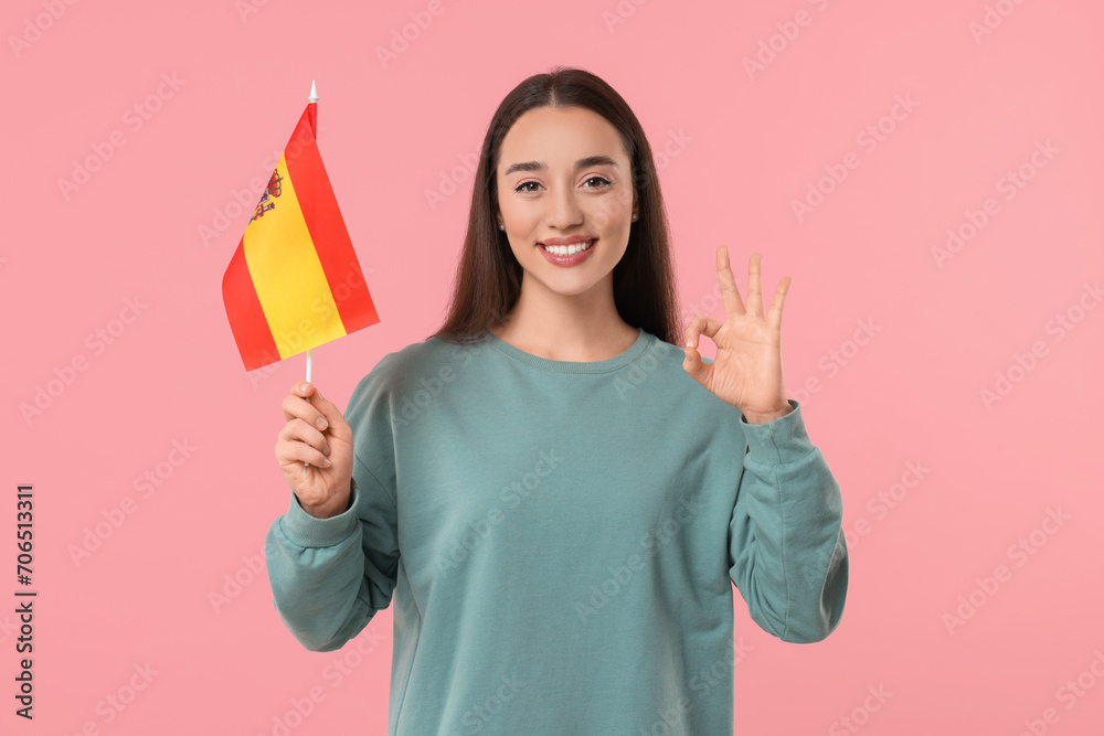 Young woman with flag of Spain showing ok gesture on pink background Young woman with flag of Spain showing ok gesture on pink background