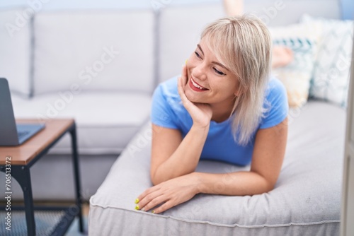 Young blonde woman smiling confident lying on sofa at home