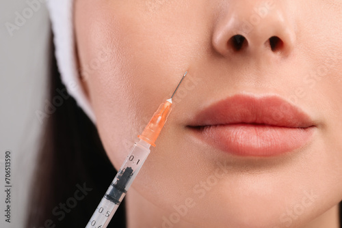 Young woman getting facial injection on light grey background  closeup. Cosmetic surgery