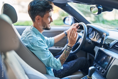 Young hispanic man smiling confident driving car at street