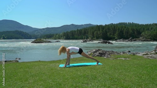 Yoga session in mountain river view. Young athletic girl training in cliffy mountains during sunrise, doing various yoga poses - healthy lifestyle concept 4k footage photo