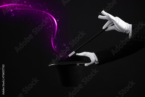 Magician showing trick with wand and top hat on black background, closeup