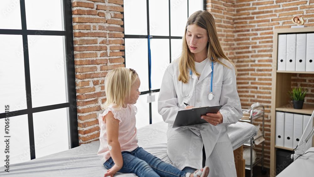 Cute child patient and caring pediatric doctor together, sitting in clinic's cozy room while writing up detailed medical report Cute child patient and caring pediatric doctor together, sitting in clinic's cozy room while writing up detailed medical report