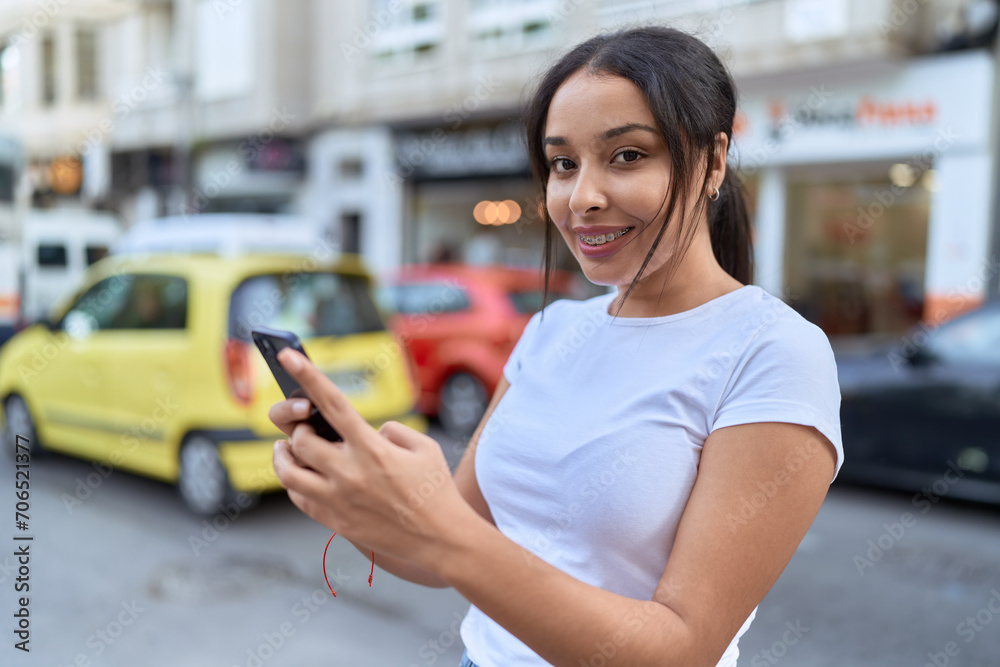 Young arab woman smiling confident using smartphone at street