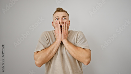 Shocked young caucasian man with a beard against a white background, expressing surprise with hands on face.