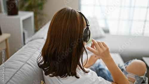 Young woman listening to music sitting on sofa at home