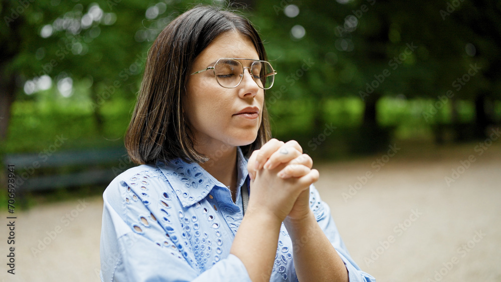 Young beautiful hispanic woman praying with closed eyes at the park in Vienna