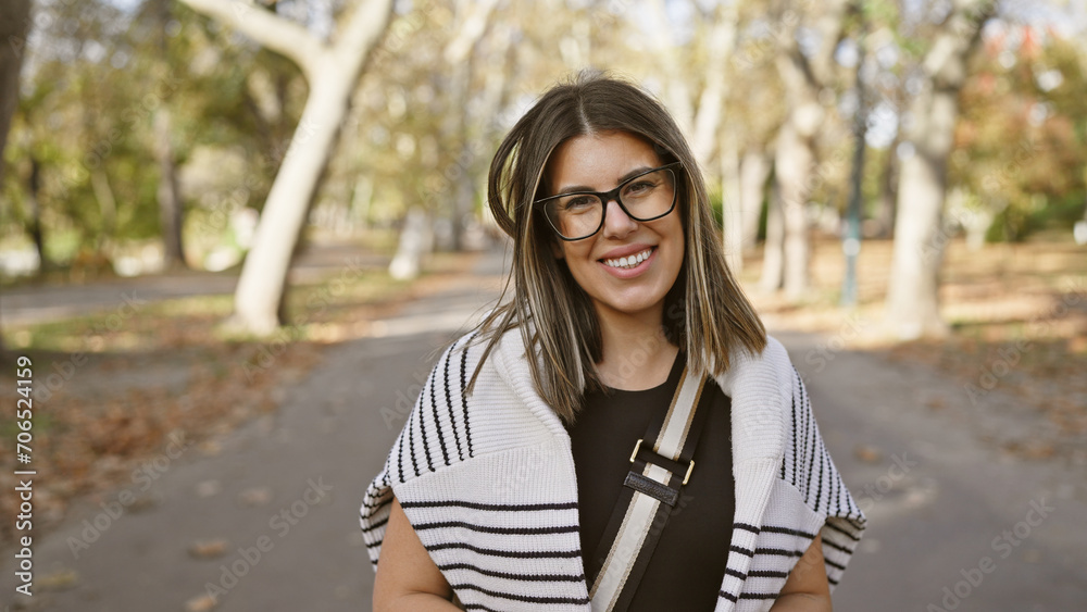 A cheerful young hispanic woman with glasses smiles in a leaf-strewn autumn park, exuding natural beauty and tranquility. A cheerful young hispanic woman with glasses smiles in a leaf-strewn autumn park, exuding natural beauty and tranquility.