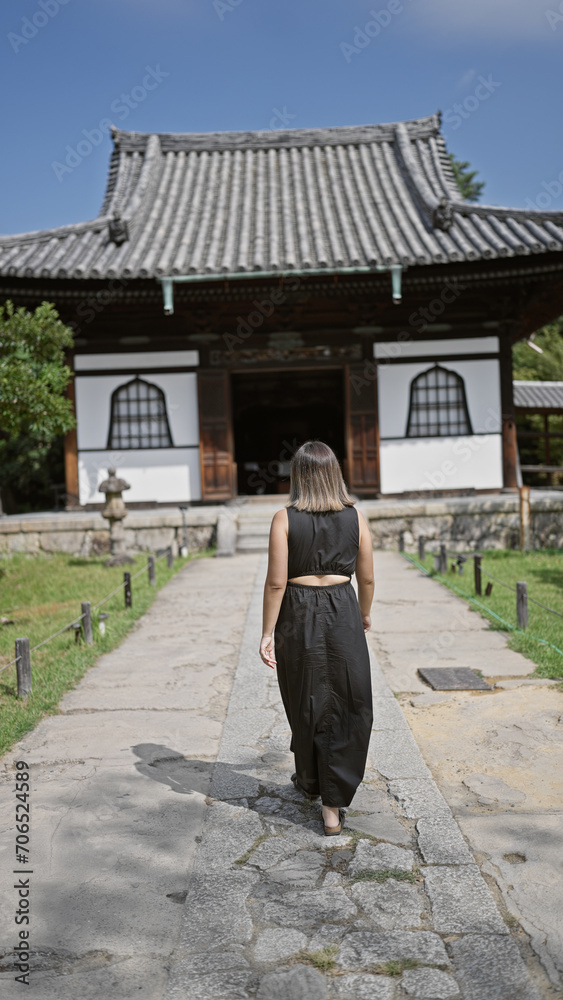 Captivating rear view of a beautiful hispanic woman in glasses, walking away leisurely, immersed in the tranquility of kodaiji temple, kyoto