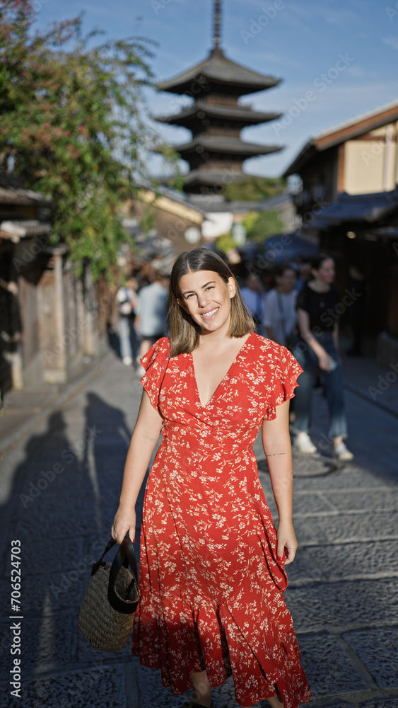 Beautiful hispanic woman smiling joyfully, confidently posing, standing on the old traditional streets of gion, kyoto, her sunny, carefree nature shining through for a fun-filled japan adventure.