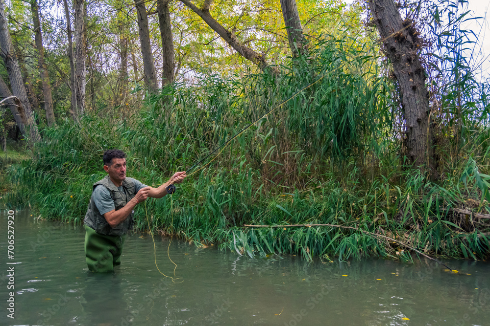 Angler in the water of a river with a wader pulling the rod. Angler in the water of a river with a wader pulling the rod.