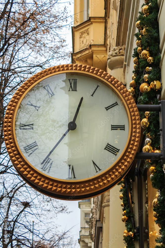 Fototapeta premium A big clock in a rich district of the streets of Prague. The clock is mounted on a wall of a building