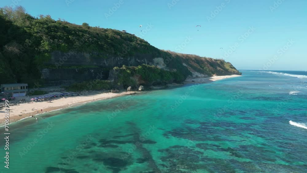 Pandawa Beach with crystal-clear blue sea waters, white sands, coastal rocks, and lush vegetation growing on the roadside cliffs. Aerial drone view. Pandawa Beach with crystal-clear blue sea waters, white sands, coastal rocks, and lush vegetation growing on the roadside cliffs. Aerial drone view.
