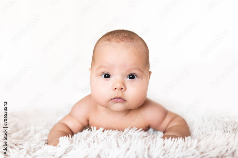 Portrait of an infant on a white background. Portrait of a baby lying on his belly against a white background Portrait of an infant on a white background. Portrait of a baby lying on his belly against a white background