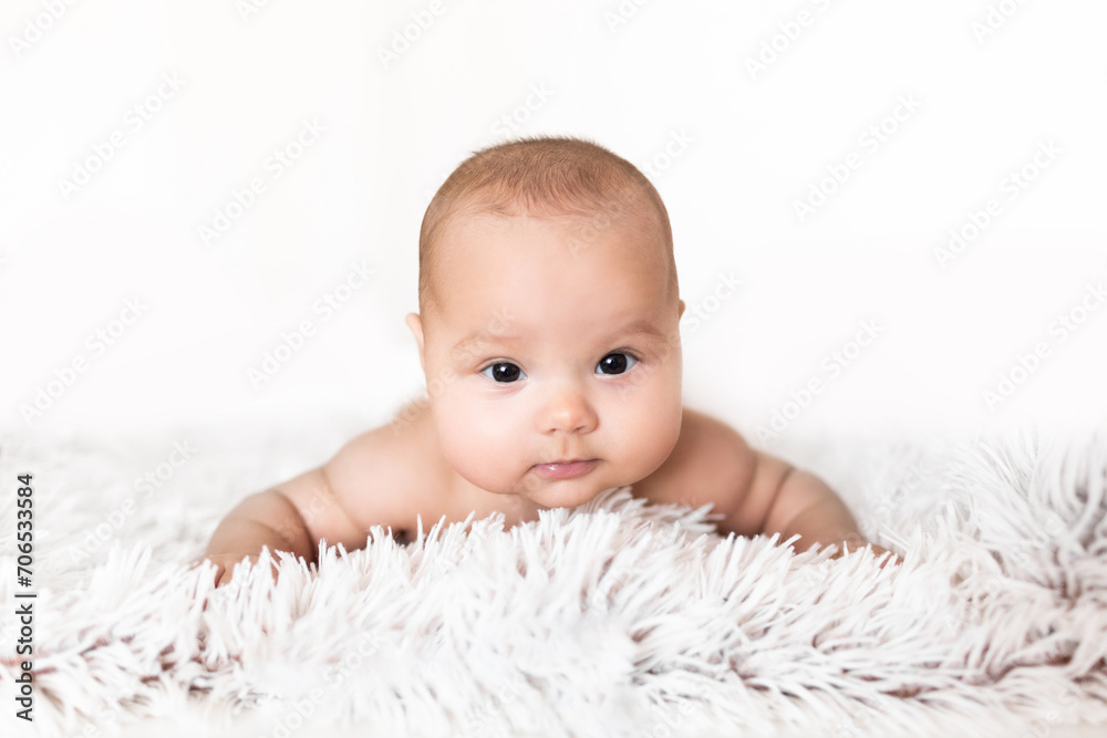 Portrait of an infant on a white background. Portrait of a baby lying on his belly against a white background Portrait of an infant on a white background. Portrait of a baby lying on his belly against a white background