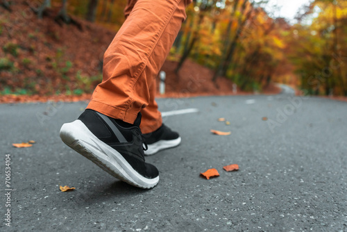 Autumn Day: Person Walking on Yellow Leaf-Covered Road Wearing Sports Shoes