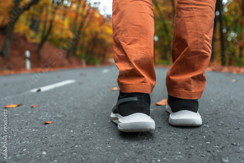 Autumn Day: Person Walking on Yellow Leaf-Covered Road Wearing Sports Shoes