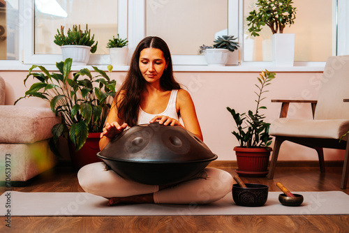 Beautiful young woman playing handpan musical instrument. Sound healing concept. photo