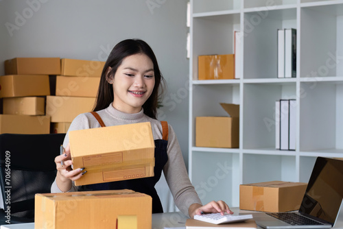Startup SME small business entrepreneur SME or freelance Asian woman using a laptop with box, online marketing packaging box and delivery, SME concept. © wichayada