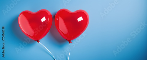 2 big red heart shaped balloons floating on the day of love and friendship on a blue background