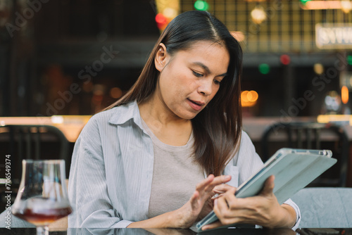 Portrait of beautiful asian woman with smartphone, relaxing in cafe, sitting and enjoying coffee while using tablet remote work business schedule planner.