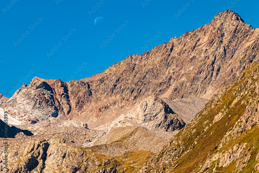 Alpine summer view with the moon touching a summit ridge at Lake Rifflsee, Mandarfen, Imst, Tyrol, Austria