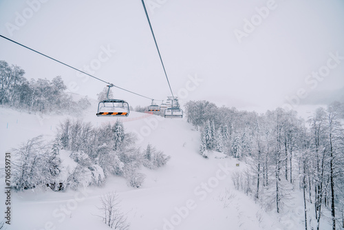 Colorful chairlift on a snow-covered mountain above a coniferous forest