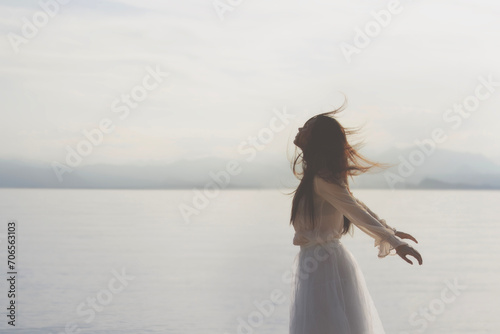 vital young woman with her hair blowing in the wind in front of the lake, concept of freedom and youth
