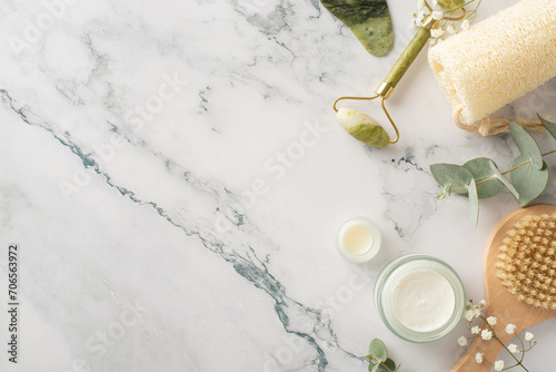 Eco-friendly hygiene setup. Flat lay top view arrangement with gua sha tools, skincare essentials, cream jars, anticellulite brush, loofah, eucalyptus, gypsophila on marble, offering space for text photo