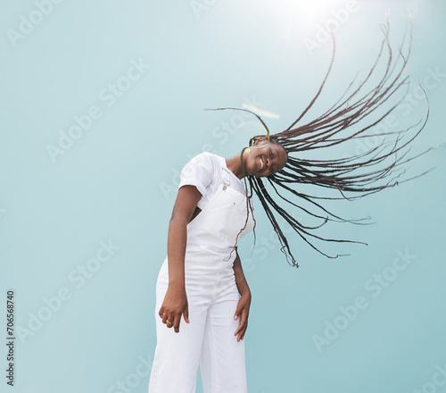Young happy female in white casuals having fun against the blue wall. Girl with long braids enjoying a sunny day.