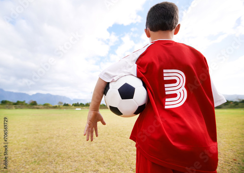 Child, back view and soccer player on field for practice, workout and ready for training on grass. Boy, athlete and ball for exercising and skill development, fitness and wellness or sports and match