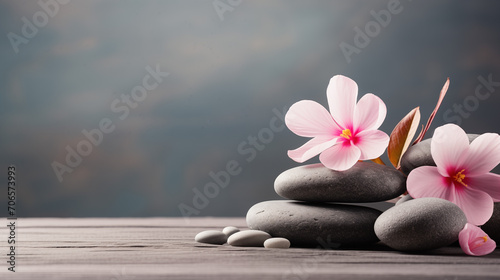 Stack of spa massage stones with pink flowers wellness background