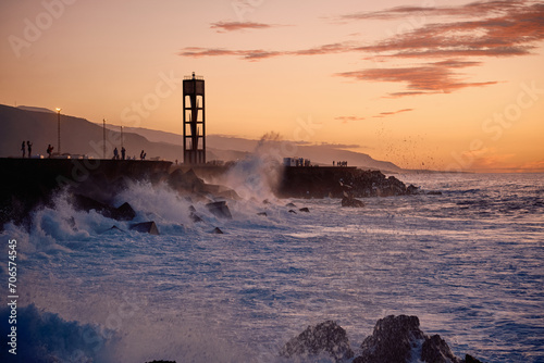 Waves spraying with view quay at sunset pink and orange in Tenerife, Spain