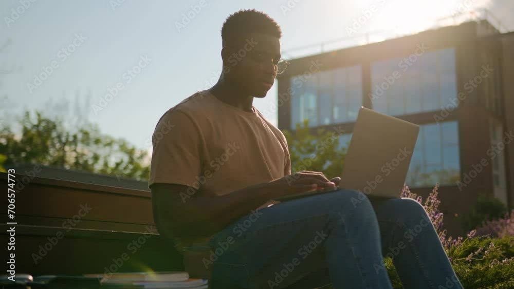 African American man student guy studying outdoors with computer male study in city near university college campus pensive looking away thinking homework task online learning with laptop in sunshine