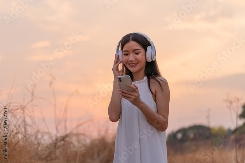 Cute beautiful girl in a meadow field with headphone and phone